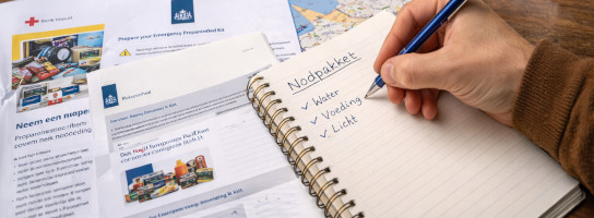 Notities, checklist en basisproducten voor een noodpakket op tafel